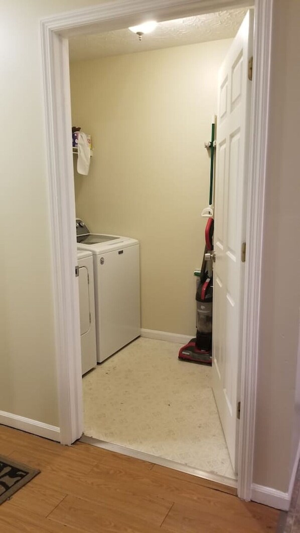 A laundry room with a washing machine, dryer, and vacuum cleaner.