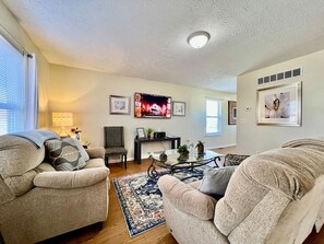 A living room with two armchairs, a coffee table, a TV, and framed pictures on the wall.