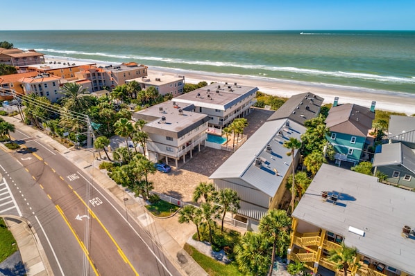 An aerial view of a coastal hotel with multiple buildings, a beach, and a clear view of the ocean.