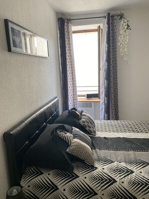 Cozy retreat with a patterned bedspread, leather headboard, and framed artwork.
