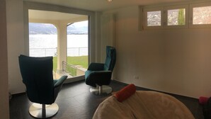 A modern room with a view of a lake and mountains, featuring two chairs and a large window. - Remarkable 4-bed Villa in Bellano (Bellano)