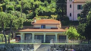 A two-story house with a red roof, a balcony, and a dock with boats. - Remarkable 4-bed Villa in Bellano (Bellano)