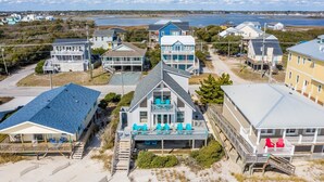 A coastal property with multiple buildings, including a prominent house with a balcony and outdoor seating area. - Oceanfront Getaway In Surf City (Surf City)