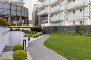 Guests can enjoy stunning views from the balconies with glass railings, surrounded by a well-maintained lawn and paved pathway.