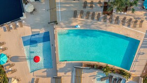 An aerial view of a resort with a large curved pool, sun loungers, and a separate section with a smaller pool and umbrellas. - One of kind 3 bedroom Villa with Ocean/Lagoon Views. (Hilton Head Island)