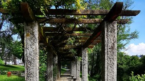 A stone pathway leading through a pergola structure in a park. - C&C apartment (Arcos de Valdevez)