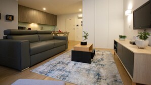 A modern living room with a grey sofa, a coffee table, and a TV mounted on the wall. - C&C apartment (Arcos de Valdevez)