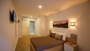 A bedroom with a large bed, bedside tables, a TV, and a painting on the wall. - C&C apartment (Arcos de Valdevez)