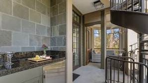 A kitchen with a granite countertop, a dining area with wicker furniture, and a spiral staircase. - Penthouse in popular, centrally located new construction neighborhood (Kiawah Island)