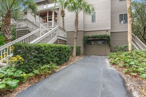 A two-story building with a covered porch, a staircase, and a gated driveway.