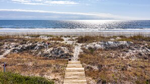 A wooden boardwalk leading to a beach with sand dunes and sparse vegetation. - Beachside Treehouse, spectacular ocean view on popular Surfsong Rd (Kiawah Island)