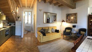 A compact living space with a kitchen, a sofa, a dining table, and a mirror. - Villa Giudici Luxury app on the Lake (Nesso)