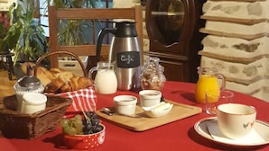 Mesa de café da manhã posta com pão, frutas, café e suco.