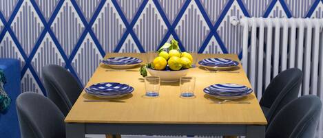 A dining area with a wooden table, six chairs, and a patterned wallpaper.