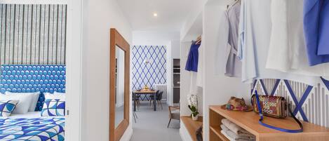 A hotel room with a bed, a wooden dresser, a mirror, a table with chairs, and a patterned wall.