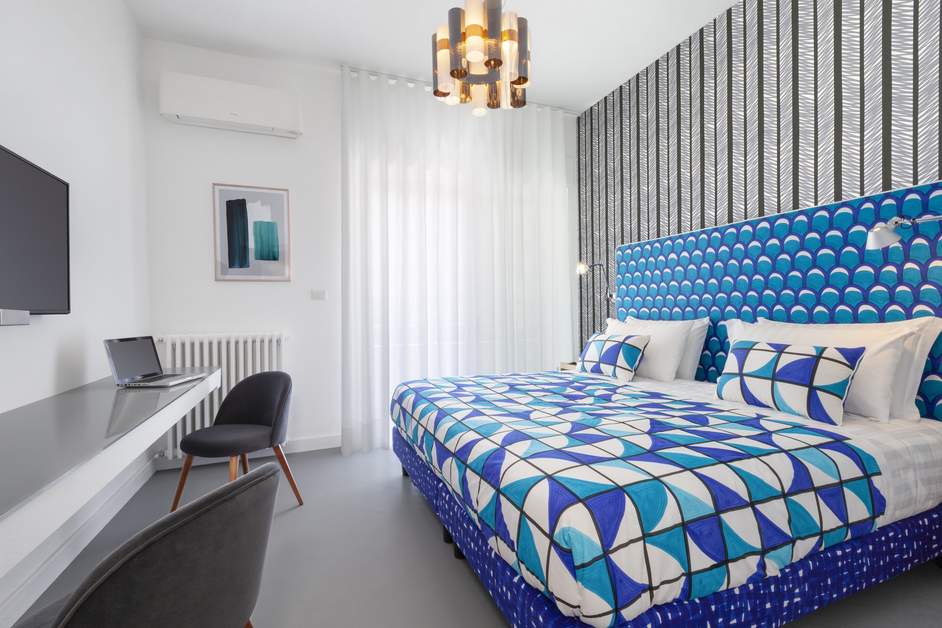 A modern hotel room with a large bed, a desk, and a chair.