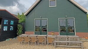A green building with two doors and a small window, surrounded by outdoor seating and artwork. - Chiristinahoeve De kasteel #7 (Boskoop)