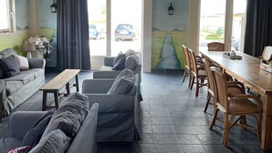 A cozy interior with wooden beams, a dining area with wicker chairs, and a sofa set. - Chiristinahoeve De kasteel #7 (Boskoop)