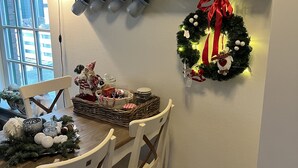 A kitchen with white cabinets, a dining table with chairs, a Christmas wreath, and a basket of gifts. - Christinahoeve Hooiberg #5 (Boskoop)