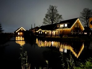 A house with multiple windows and a reflection in the water.