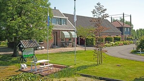 A house with a flag, a small outdoor seating area, and a pond. - Christinahoeve Hooiberg #5 (Boskoop)
