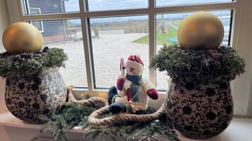 A window with two decorative pots containing Christmas ornaments and a plush toy.