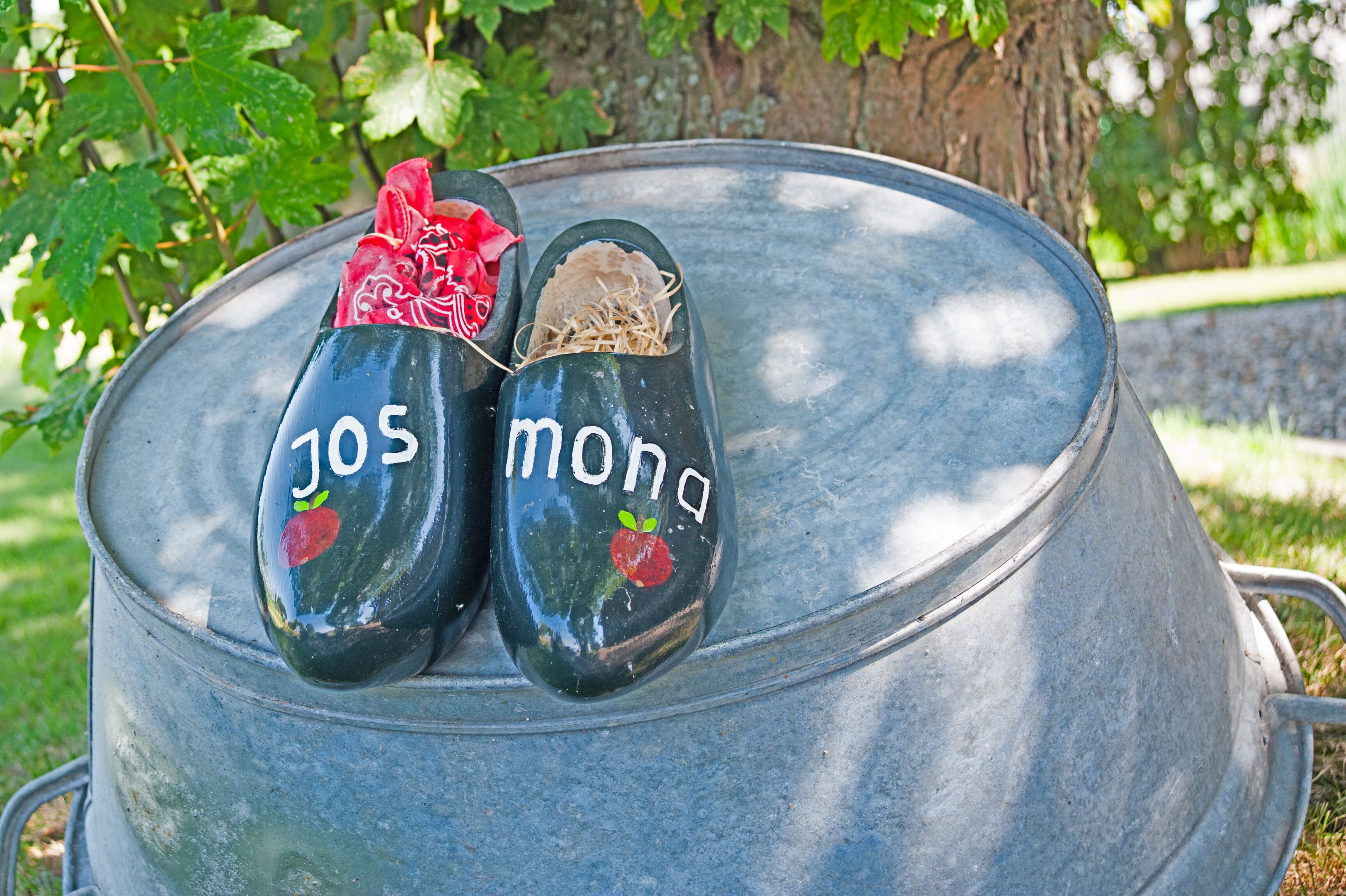 Two painted shoes with the text "jos mona" on a metal barrel.