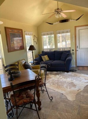 Relax in a spacious living area with a high ceiling fan, dining table, and comfortable seating area.