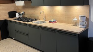A modern kitchen with dark cabinets, a stainless steel sink, and a gas stove. - Christinahoeve Oude Deel #4 (Boskoop)
