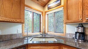 A kitchen with wooden cabinets, a granite countertop, a stainless steel sink, and a coffee maker. - WITC03 - Updated Home, Great Outdoor Space, AC, Hot Tub (Sunriver)
