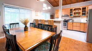 Un coin repas avec une table et des chaises en bois, une cuisine avec des placards en bois et un ventilateur de plafond.