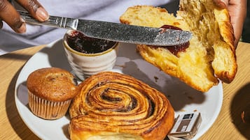 Un plato con un muffin, un rollo de canela y una rebanada de pan con mermelada.