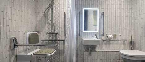 A modern bathroom with a shower, toilet, sink, and a mirror.
