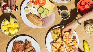 A table with various food items including sandwiches, fruit, and a cup of coffee.