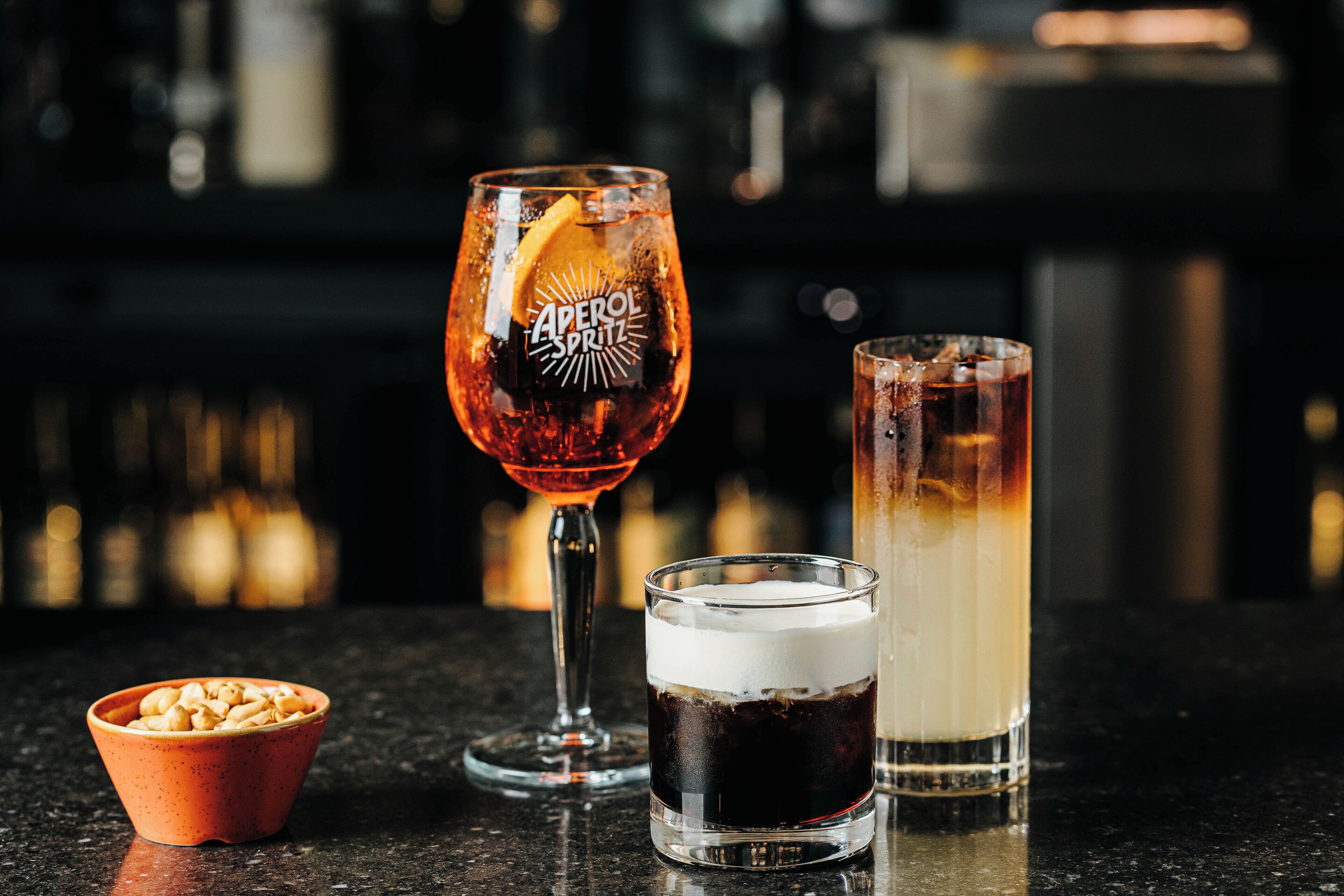 Três copos de bebidas em um balcão de bar.