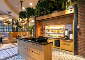 Una cocina moderna con armarios de madera, una isla central, plantas colgantes y una barra desayunadora.
