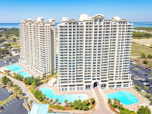 A high-rise hotel with multiple balconies, a central courtyard, and two swimming pools. - Deluxe Views-Short Walk 2 Beach-Resort Amenities (Miramar Beach)