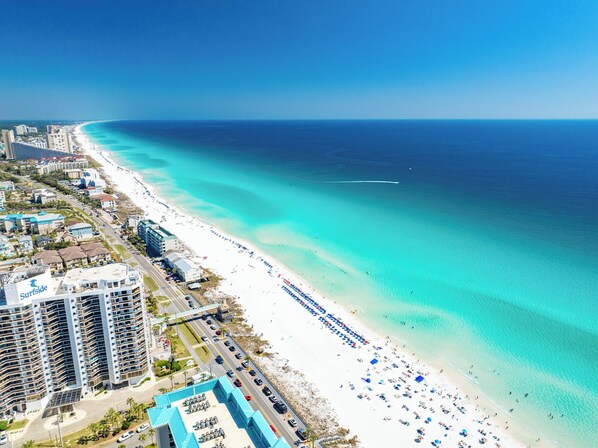 Eine Küstenstadt mit Strand, Hochhäusern und blauem Himmel.