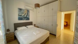A bedroom with a bed, a wardrobe, a painting, and an air conditioning unit. - Antonis House (Sifnos)