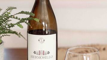 A bottle of Hermosillo Pinot Noir wine next to a glass filled with red wine, placed on a textured surface.
