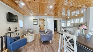 A modern living room with a wooden ceiling, a flat-screen TV, a sofa, a coffee table, and a dining area with a table and chairs. - Hill house 2 bedroom, 2 bath house. Walk to downtown Hill City, SD (Hill City)