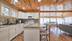 A spacious kitchen with a central island, white cabinets, and a microwave. There is a dining area with a table and chairs, and a large window providing natural light. - Hill house 2 bedroom, 2 bath house. Walk to downtown Hill City, SD (Hill City)