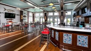 Zona de bar moderna con techo alto, ventanas amplias y diversas opciones de asiento.