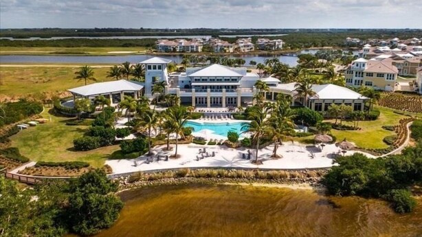 Un gran resort con varias construcciones, una piscina central y palmeras circundantes.
