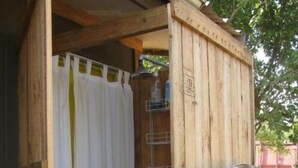 Une structure en bois avec un rideau blanc, une étagère en métal et une enseigne avec du texte.