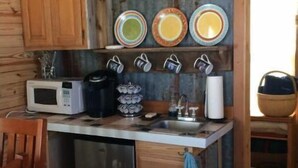 Une cuisine compacte dotée de meubles en bois, d’un four à micro-ondes, d’une machine à café et d’un évier.