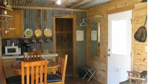 Un chalet rustique avec un intérieur en bois, une table à manger avec des chaises, un four à micro-ondes et une petite kitchenette.