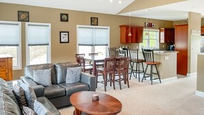 A modern living room with a leather sofa, a wooden coffee table, and a dining area with wooden chairs and a table. - Resort condo close to hiking and river/lake (Thornton)