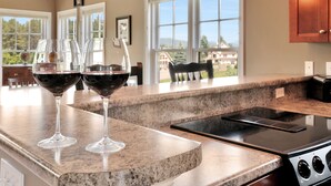 A kitchen with granite countertops, a black stove, and two wine glasses filled with red wine. - Resort condo close to hiking and river/lake (Thornton)