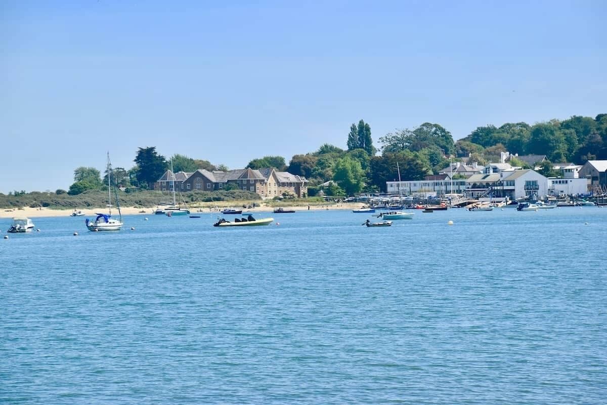 Una zona costera con barcos en el agua, edificios en la orilla y un cielo despejado.